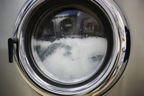 A front-loading washing machine filled with water and soap suds.