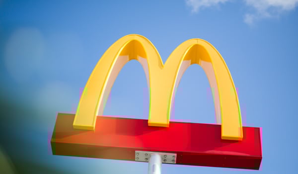 McDonald's Golden Arches signage against a blue sky.
