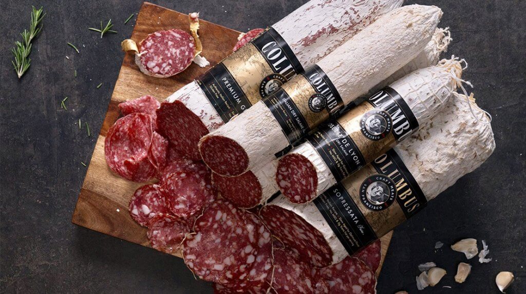Rolls of salami piled high, with pieces freshly cut from the end.