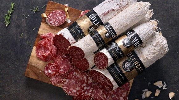 Rolls of salami piled high, with pieces freshly cut from the end.
