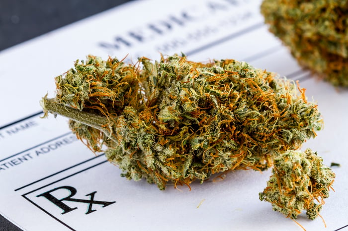 A cannabis bud lying atop a doctor's prescription pad. 