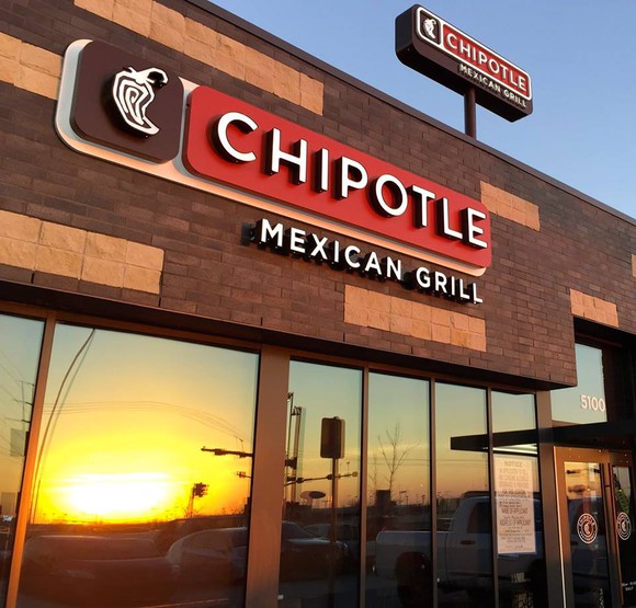 Outside front of Chipotle restaurant with a sunset reflecting in the window.