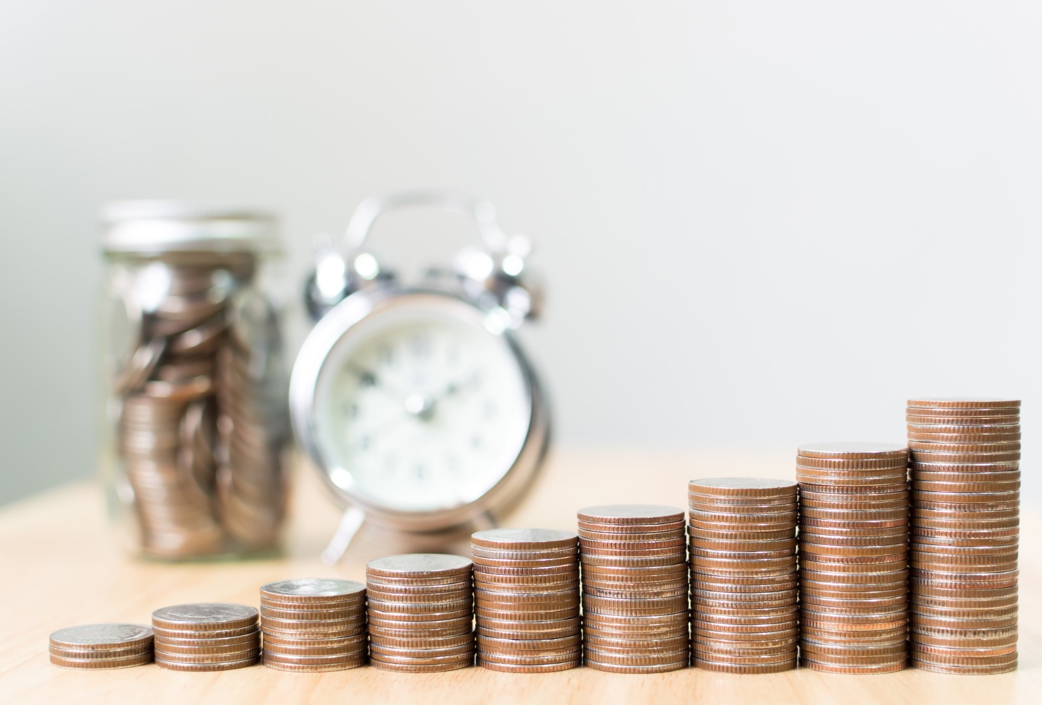 Quarters stacked in ever-increasing stacks with a clock behind.