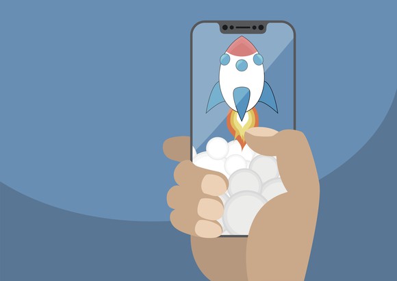 A hand holding a smartphone displaying a cartoon rocket ship taking off.