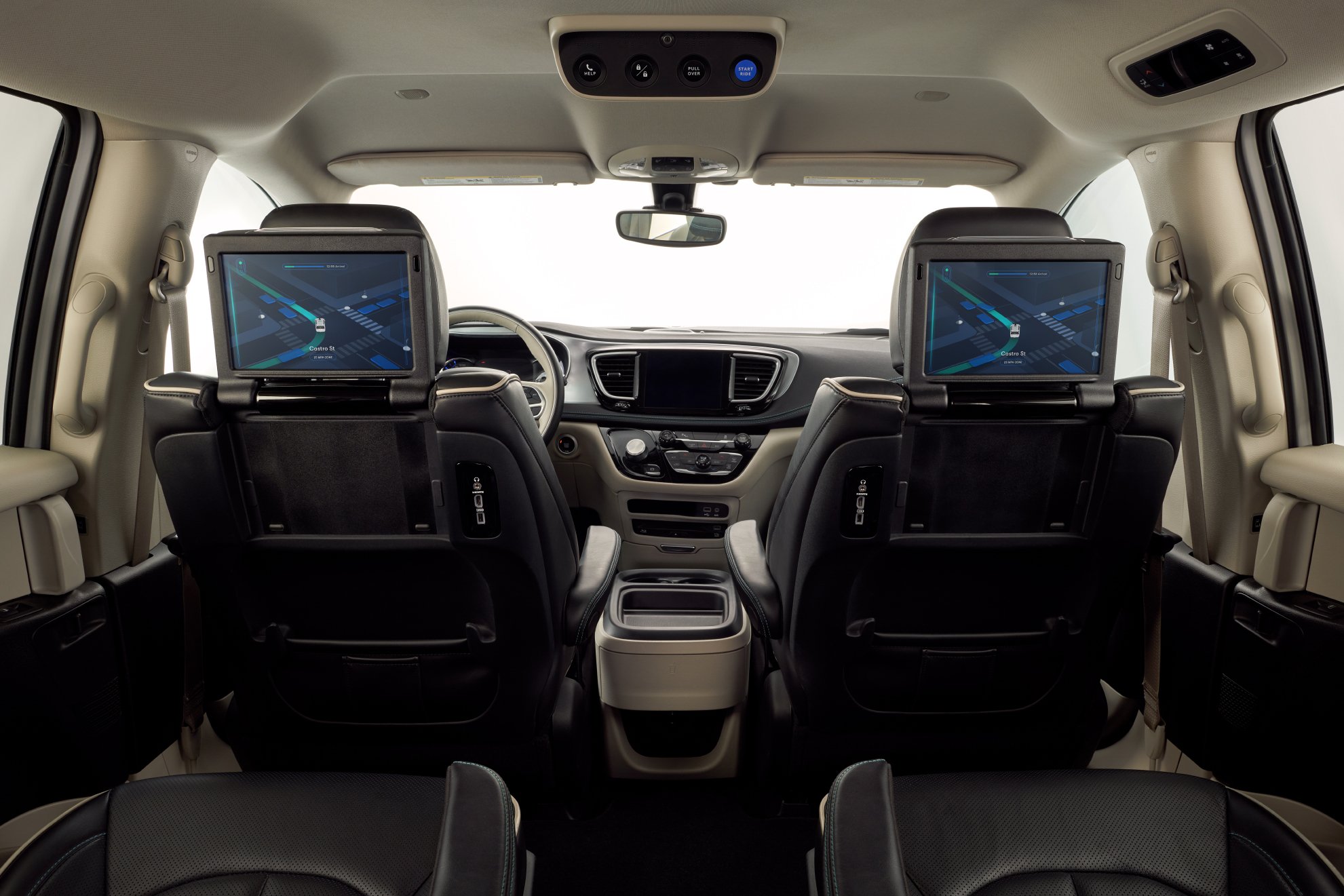The interior of Waymo's Pacifica minivan, viewed from the back seat, showing touchscreens positioned for the passengers' use. 