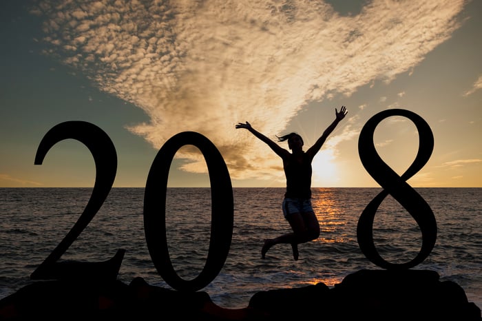 Woman jumping in front of the sea at sunrise, celebrating 2018.