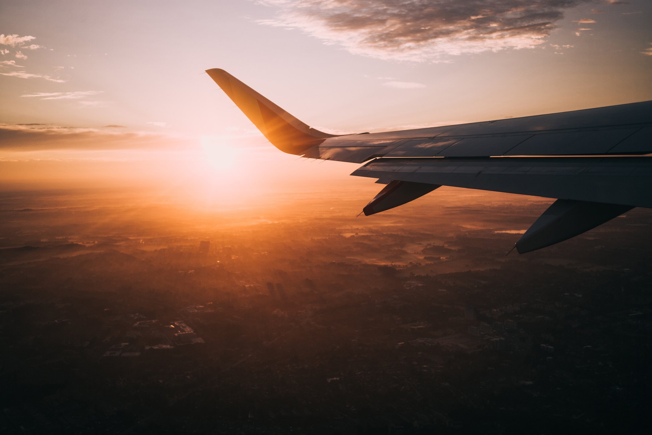 Image from inside a commercial airplane of a sunset and plane wing
