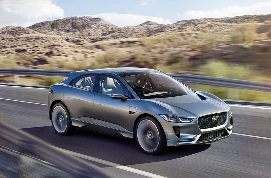 The Jaguar I-PACE in silver driving down a desert highway.