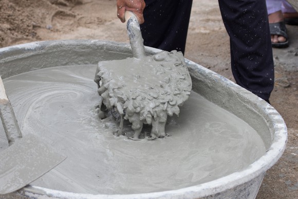 A person mixing cement with a shovel.