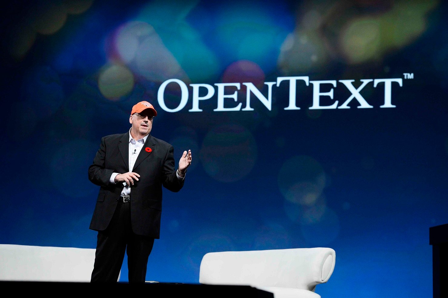 CEO Mark Barrenechea standing in front of a backdrop with the OpenText logo on it.