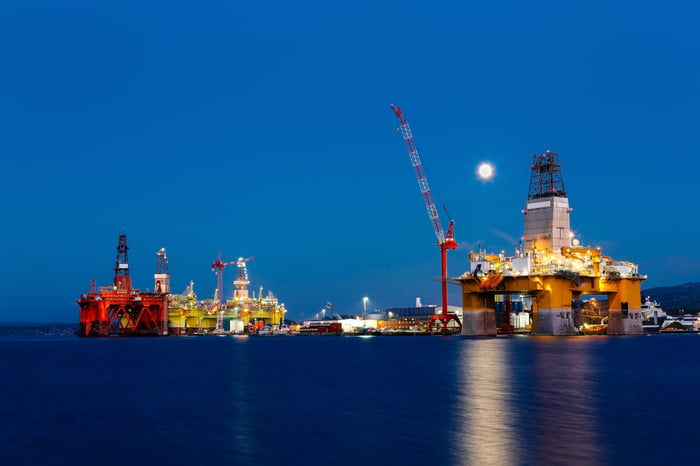 Offshore drilling rigs at a dockyard at night.