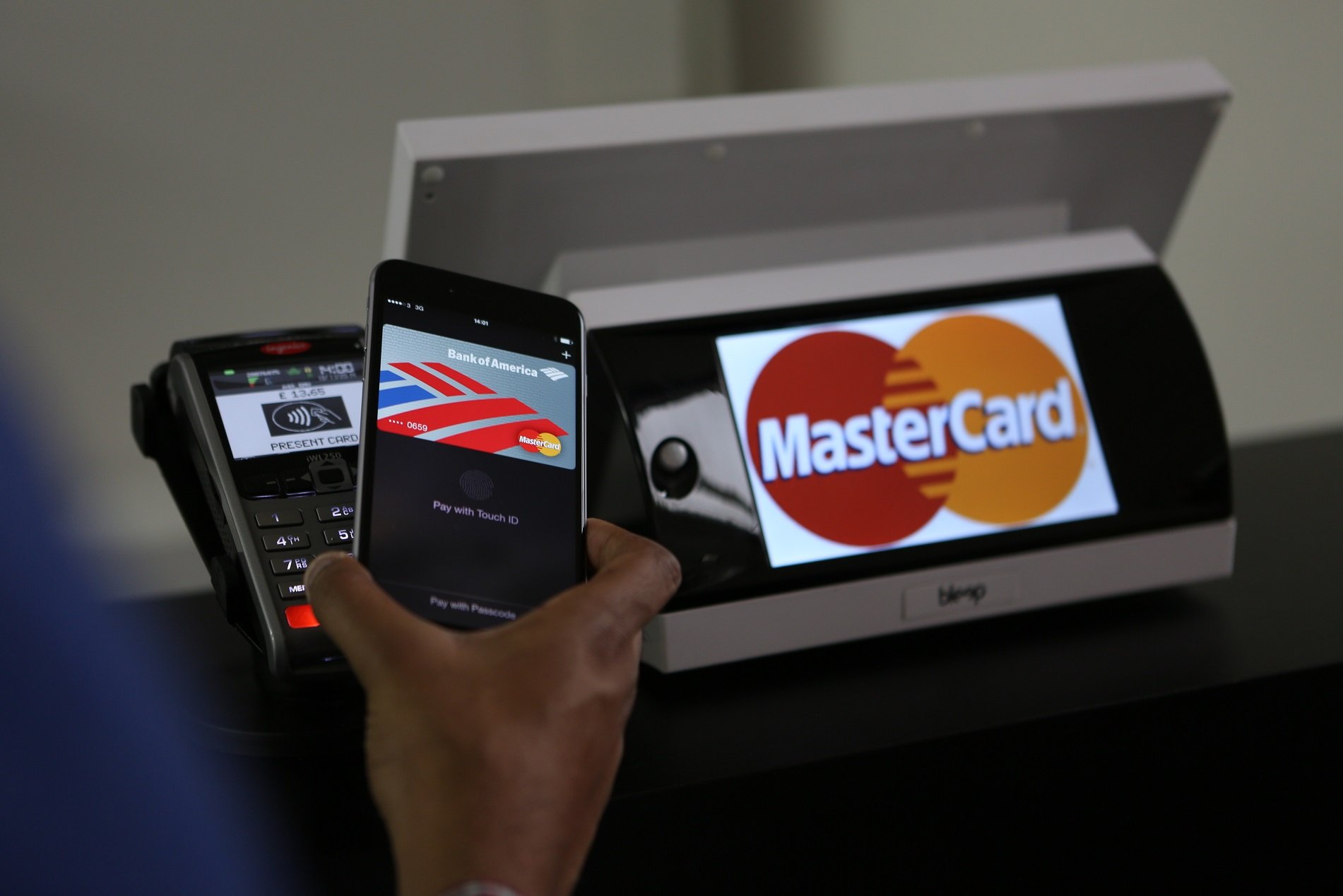 Card reader showing Mastercard logo with a mobile device on top of it.