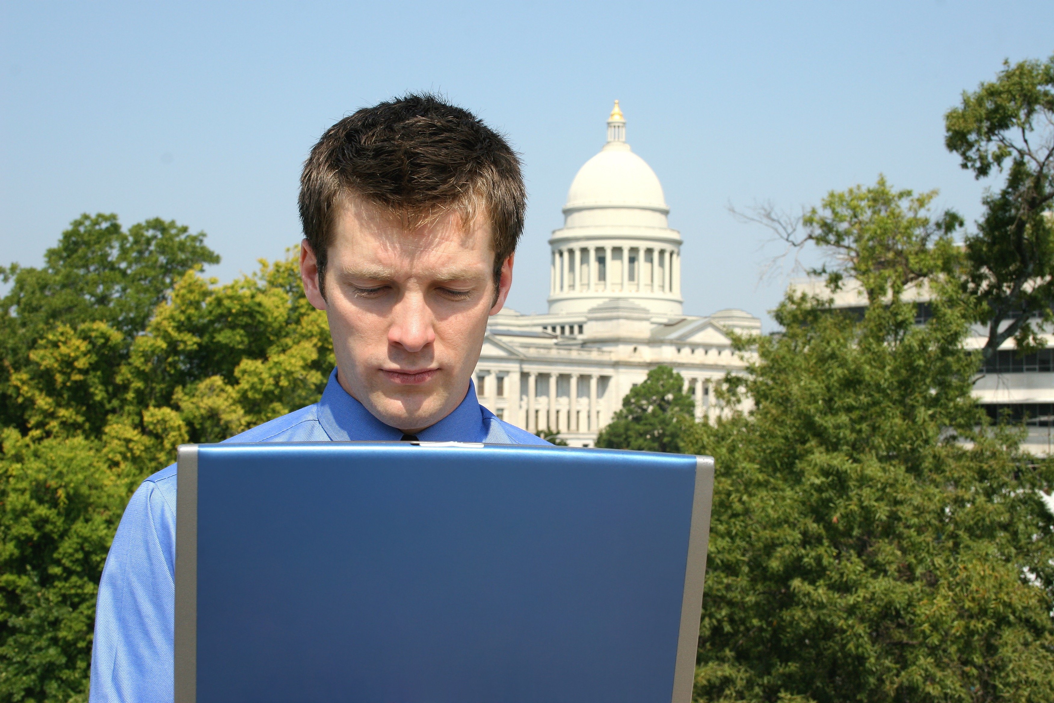 A person on a laptop with the U.S. Capitol building in the background.