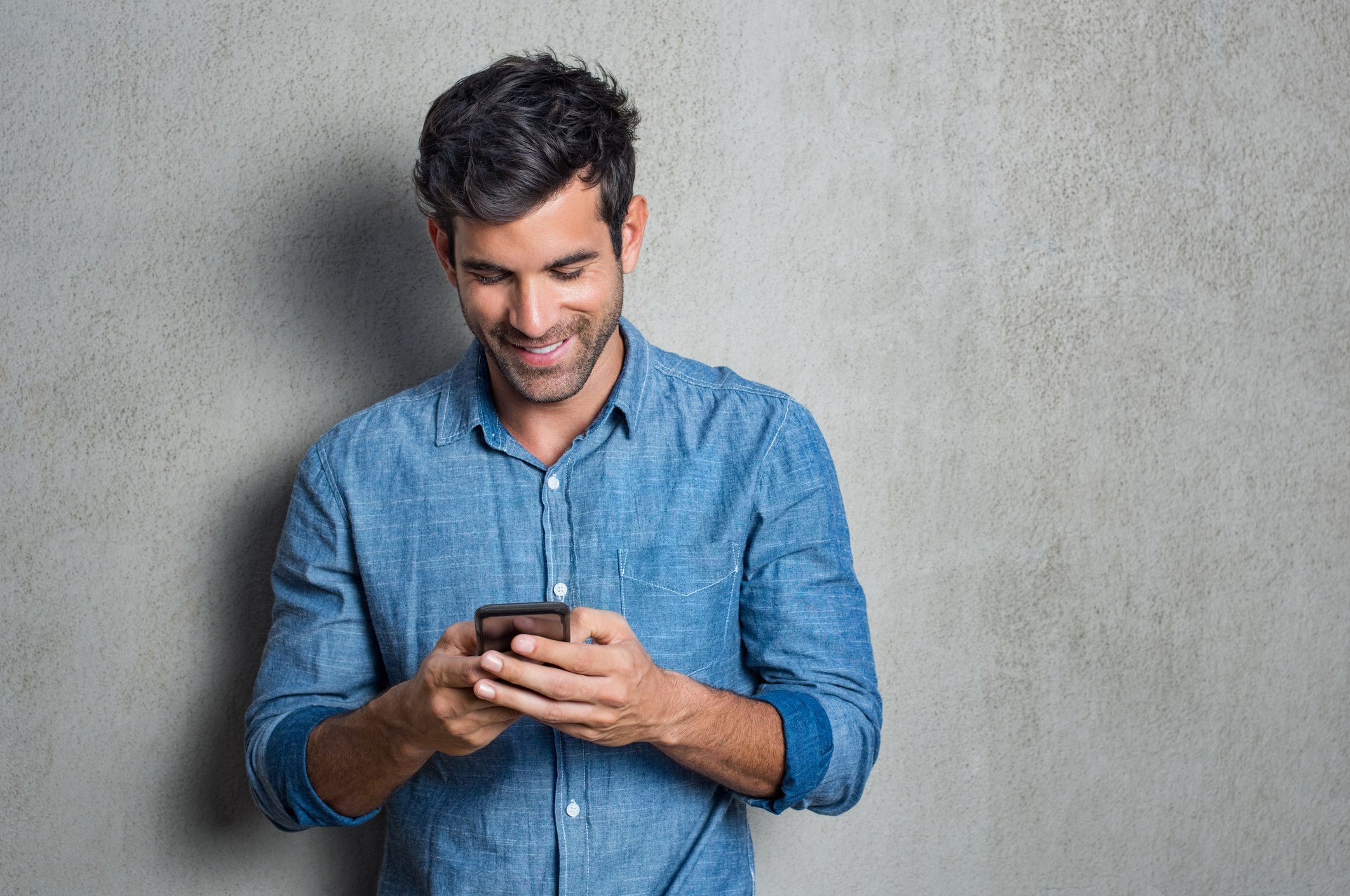 A man looks at his smartphone and smiles.