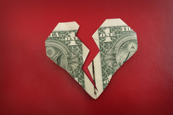 a dollar folded into a heart shape and then cut almost in half, looking like a broken heart