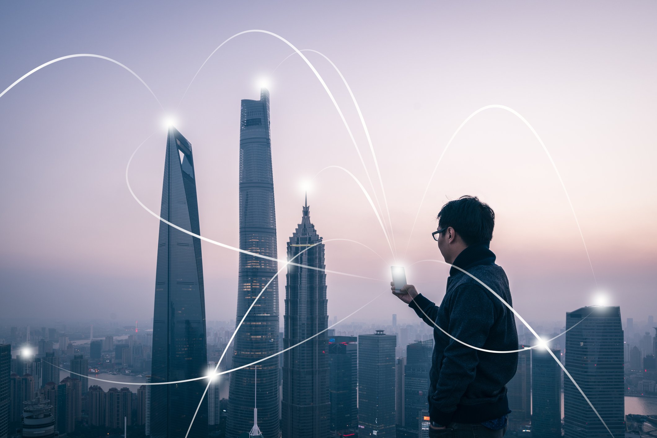 Man using wireless phone with graphic of connection to surrounding skyskrapers. 