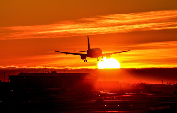 A plane landing as the sun sets