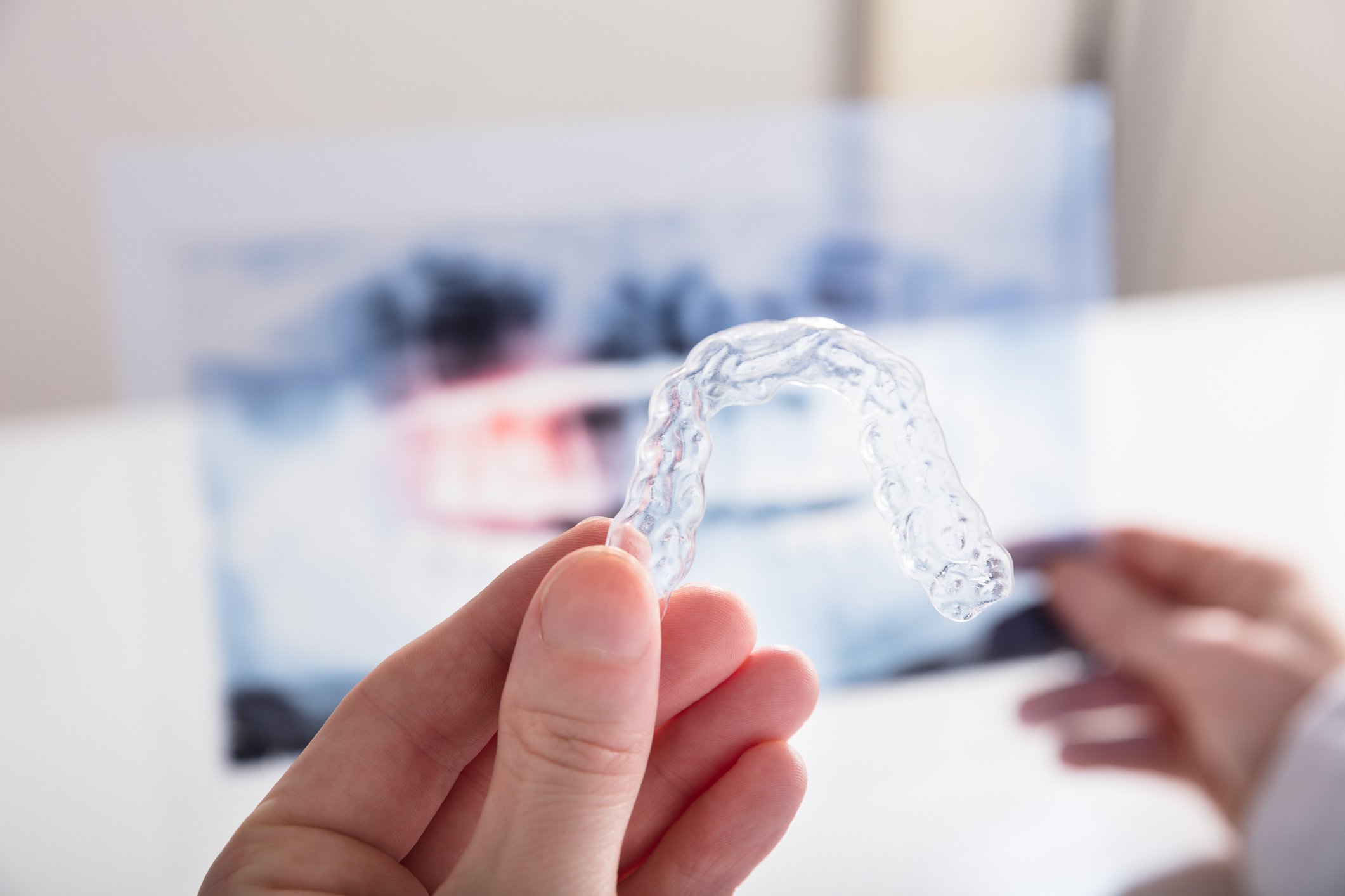 A hand holding a clear mold of a set of teeth.