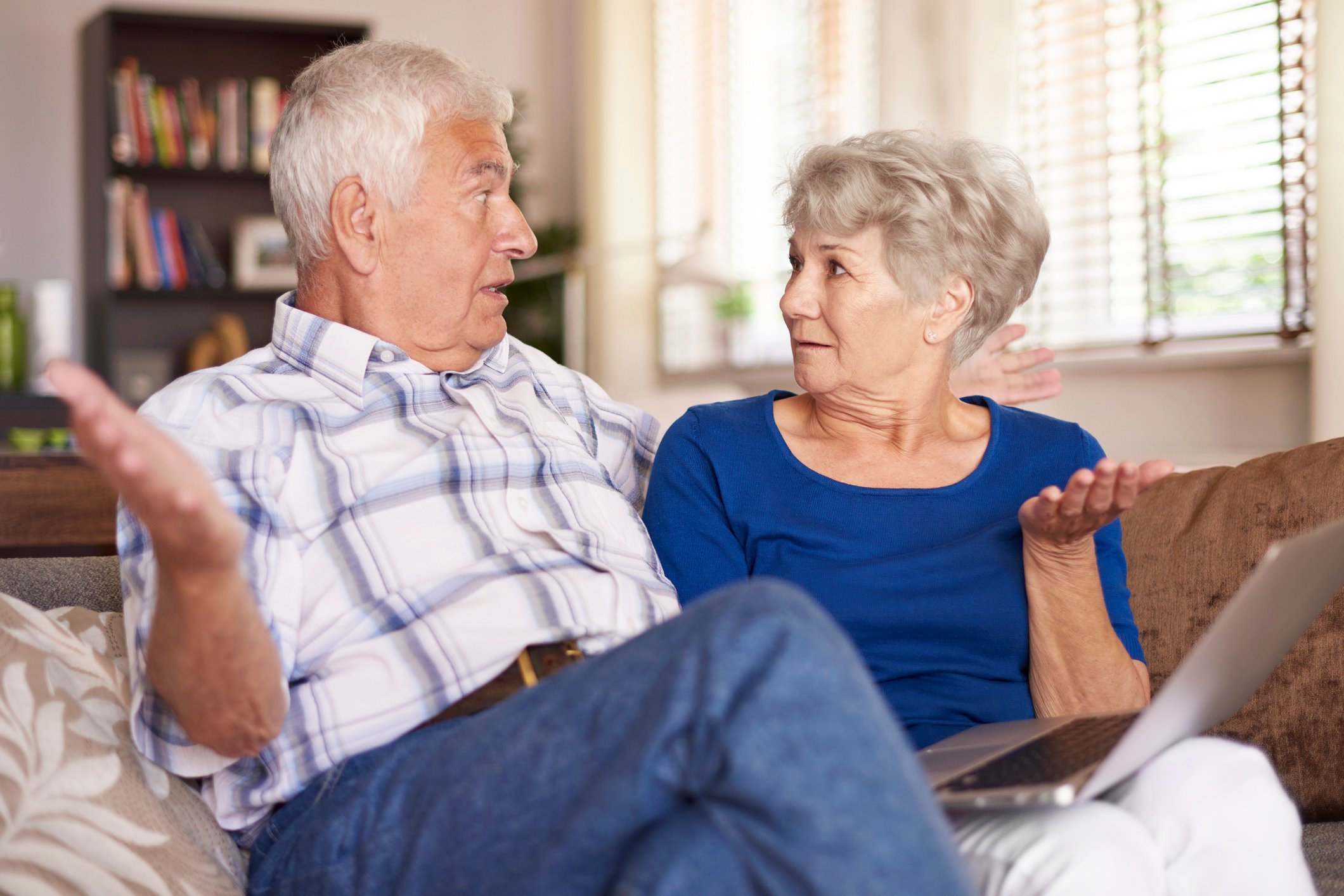 Senior couple looking at a laptop while raising their hands in confusion