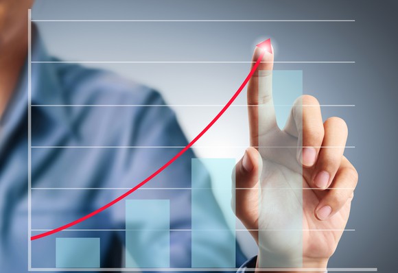 A man touching an arrow going up over a bar graph.