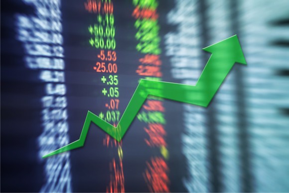 Blurred chart of asset prices with green upward arrow over them.