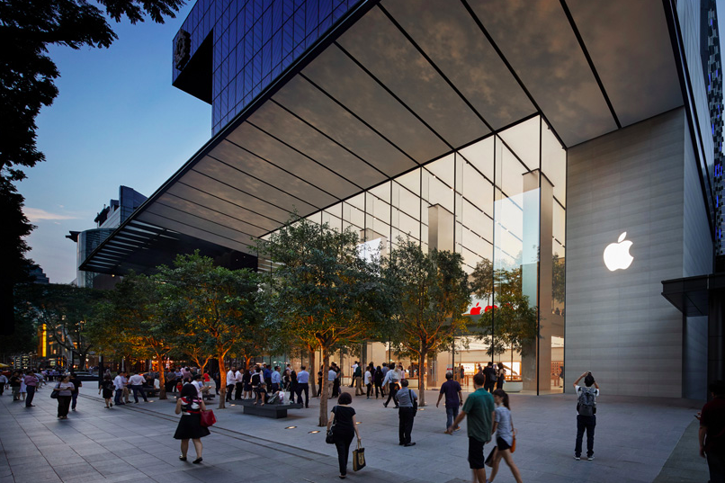 People walk into an Apple store with large glass windows