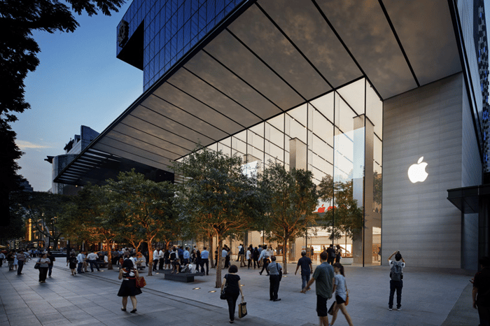 People walk into an Apple store with large glass windows