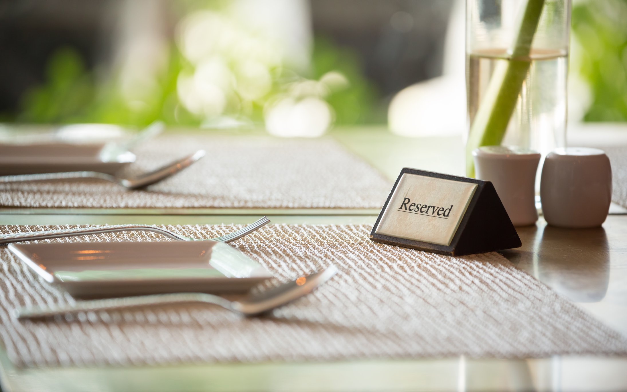 Table set with place settings, with a reserved sign next to a vase