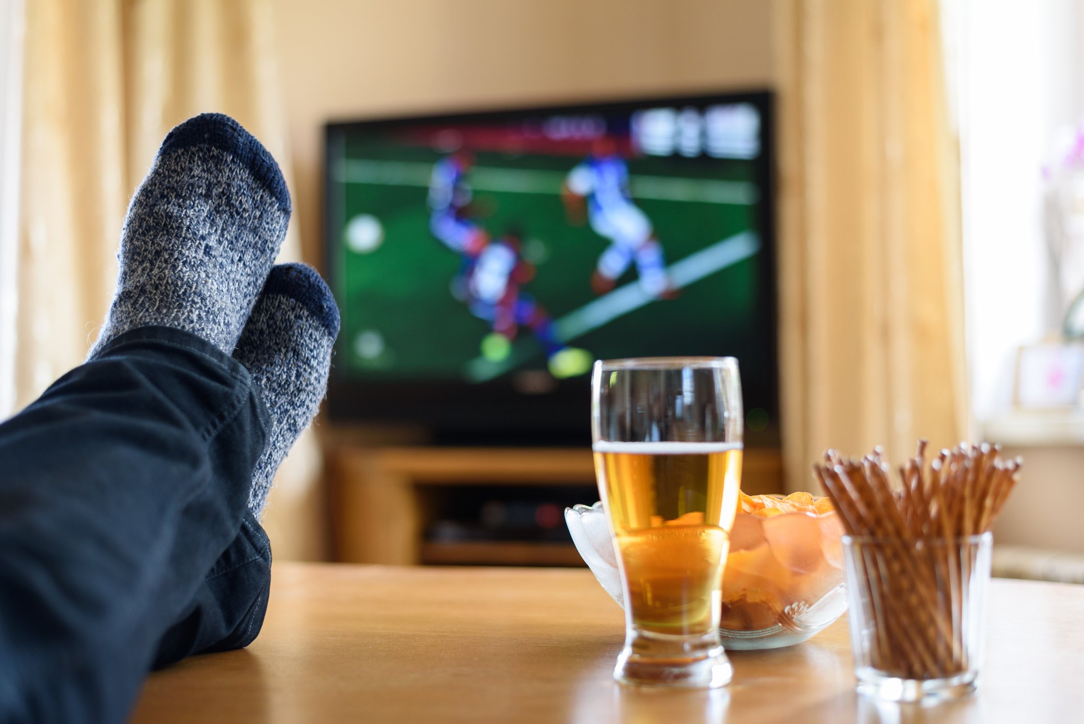A sports fan watches a soccer match from his couch.