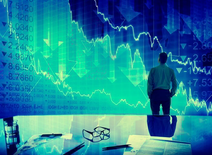 Man looking at stock prices and down arrows.