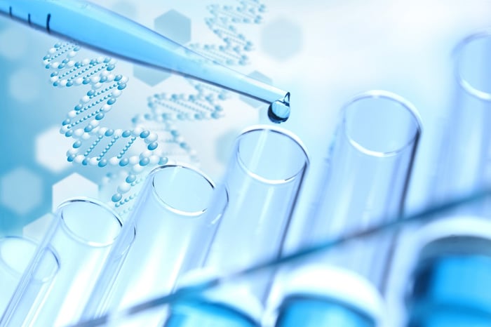 test tubes with a pipette dropping liquid in them and DNA strands in the background.