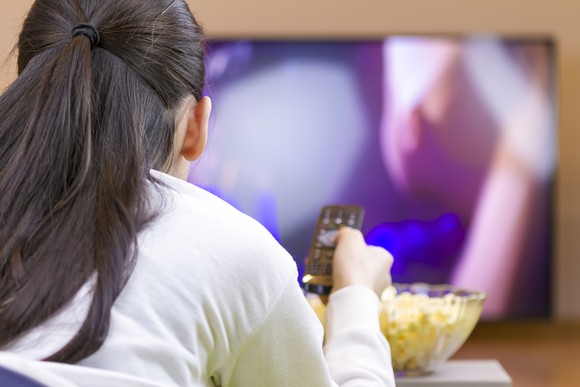 Woman watching TV eating popcorn