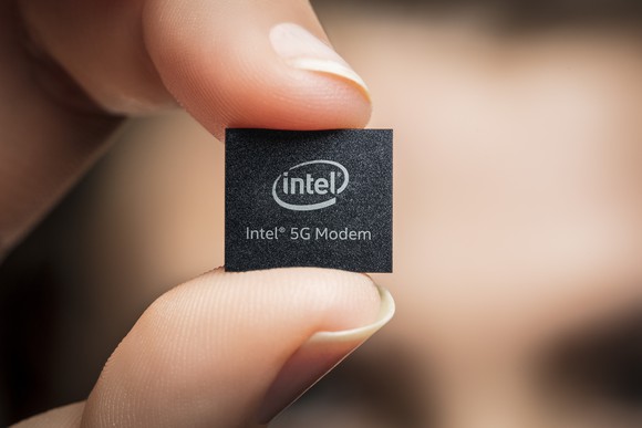 An Intel modem being held between someone's index finger and thumb.