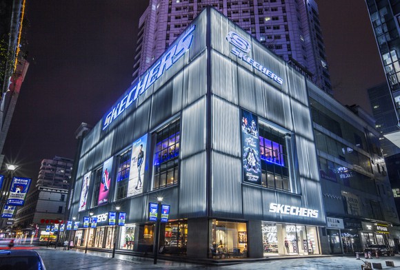 A new ultra-modern Skechers storefront in China. The building is surrounded by high rises, and has metal sheeting exterior.