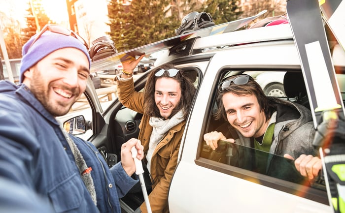 A group of friends holding skiing equipment while on vacation.