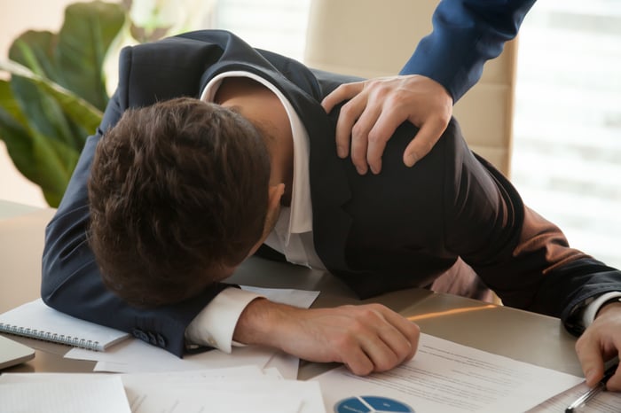 A woman has her head down on a desk.