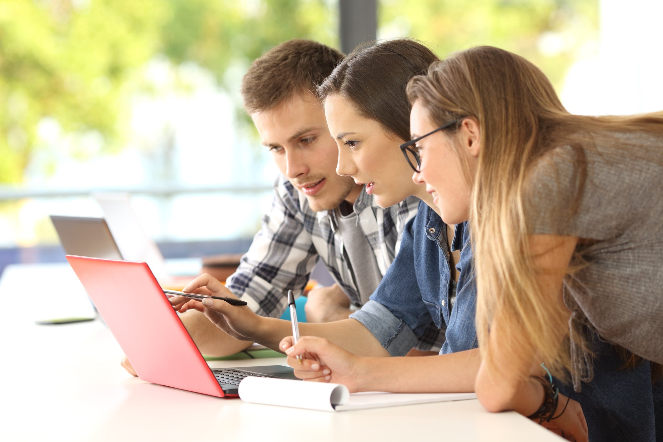 Three students looking at the same laptop screen.