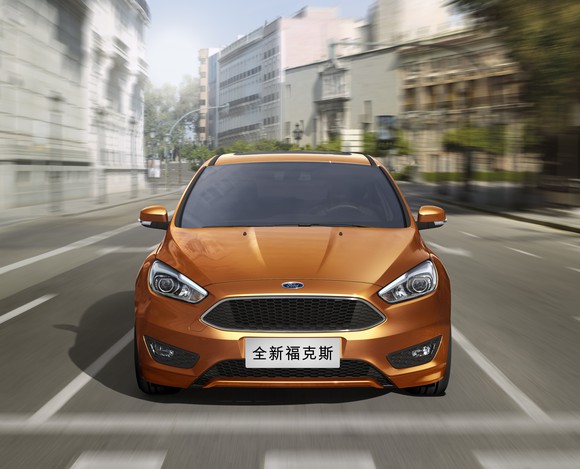 A bronze-colored Ford Focus compact sedan on a Chinese city street.