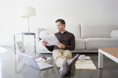 man reading stock quotes in newspaper