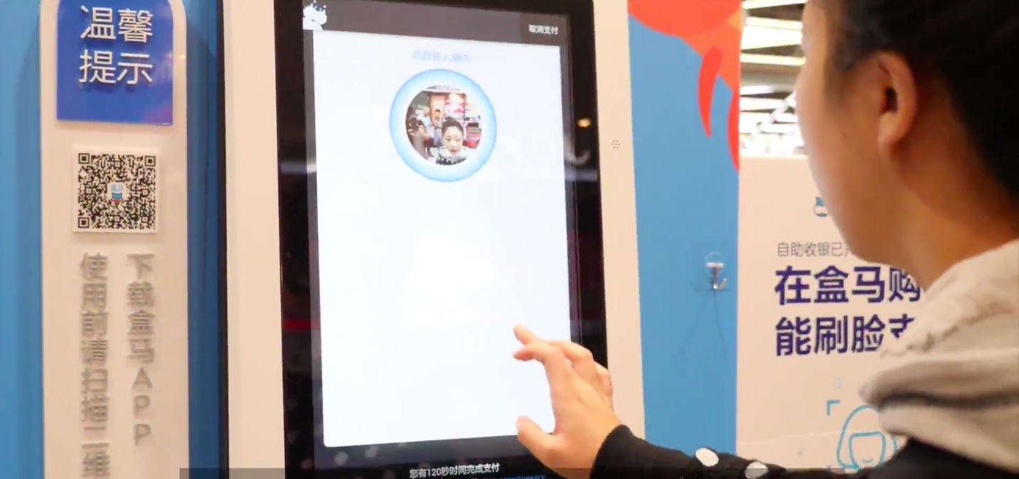 A Hema supermarket customer taps on a screen as she pays for her items using facial-recognition technology