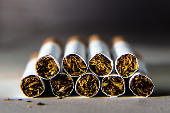 Nine cigarettes arranged in two rows on a flat surface.
