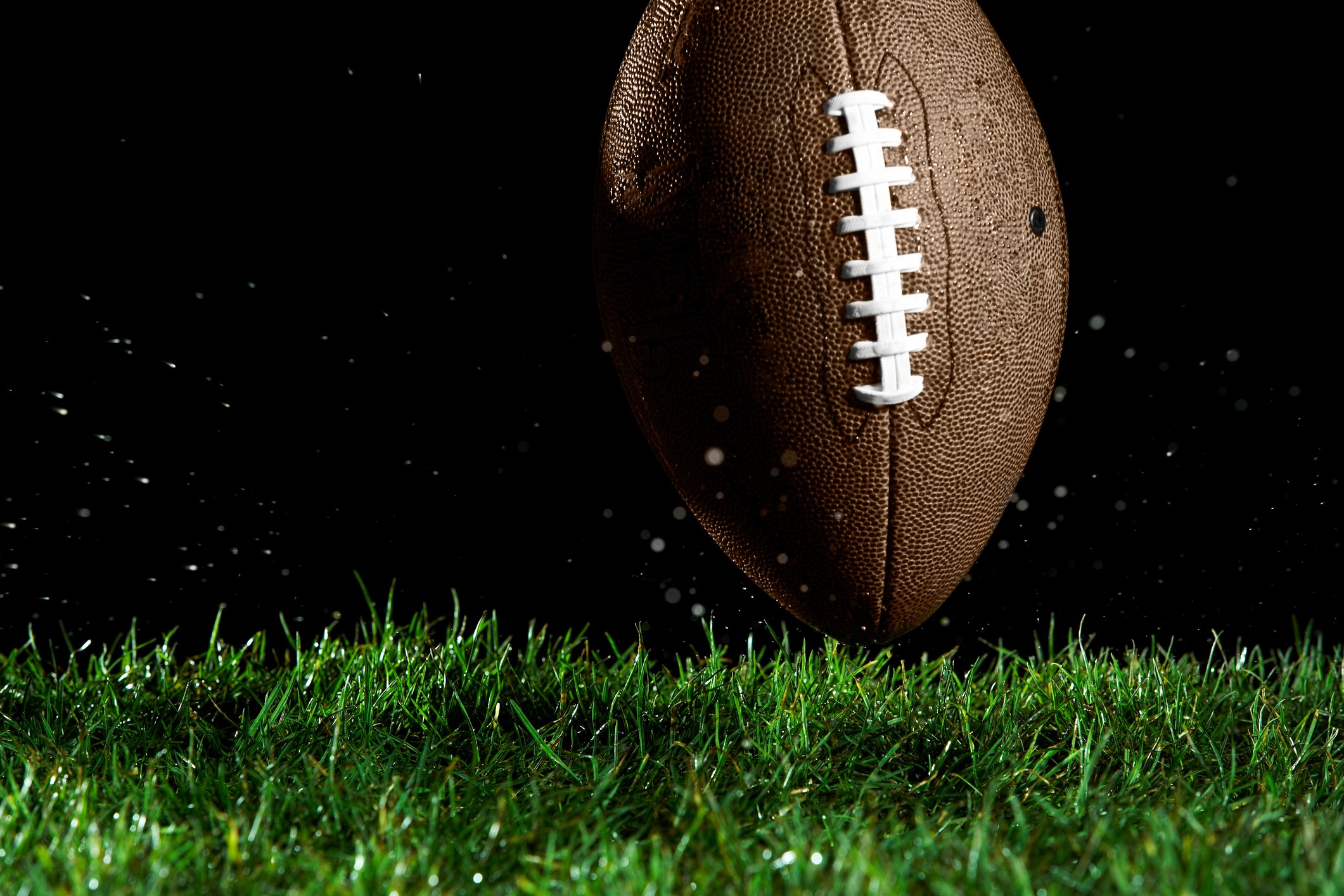 A football on turf, black background.