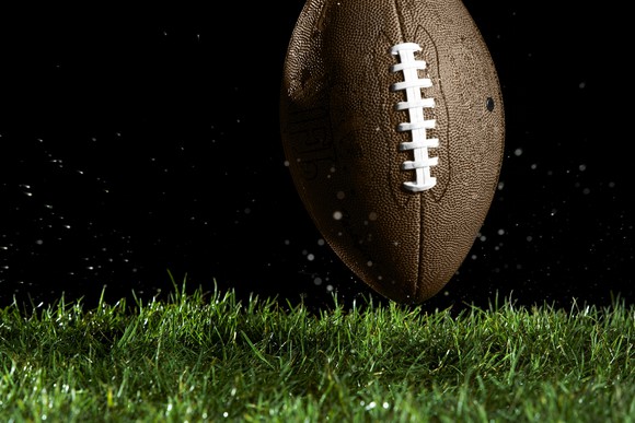 A football on turf, black background.