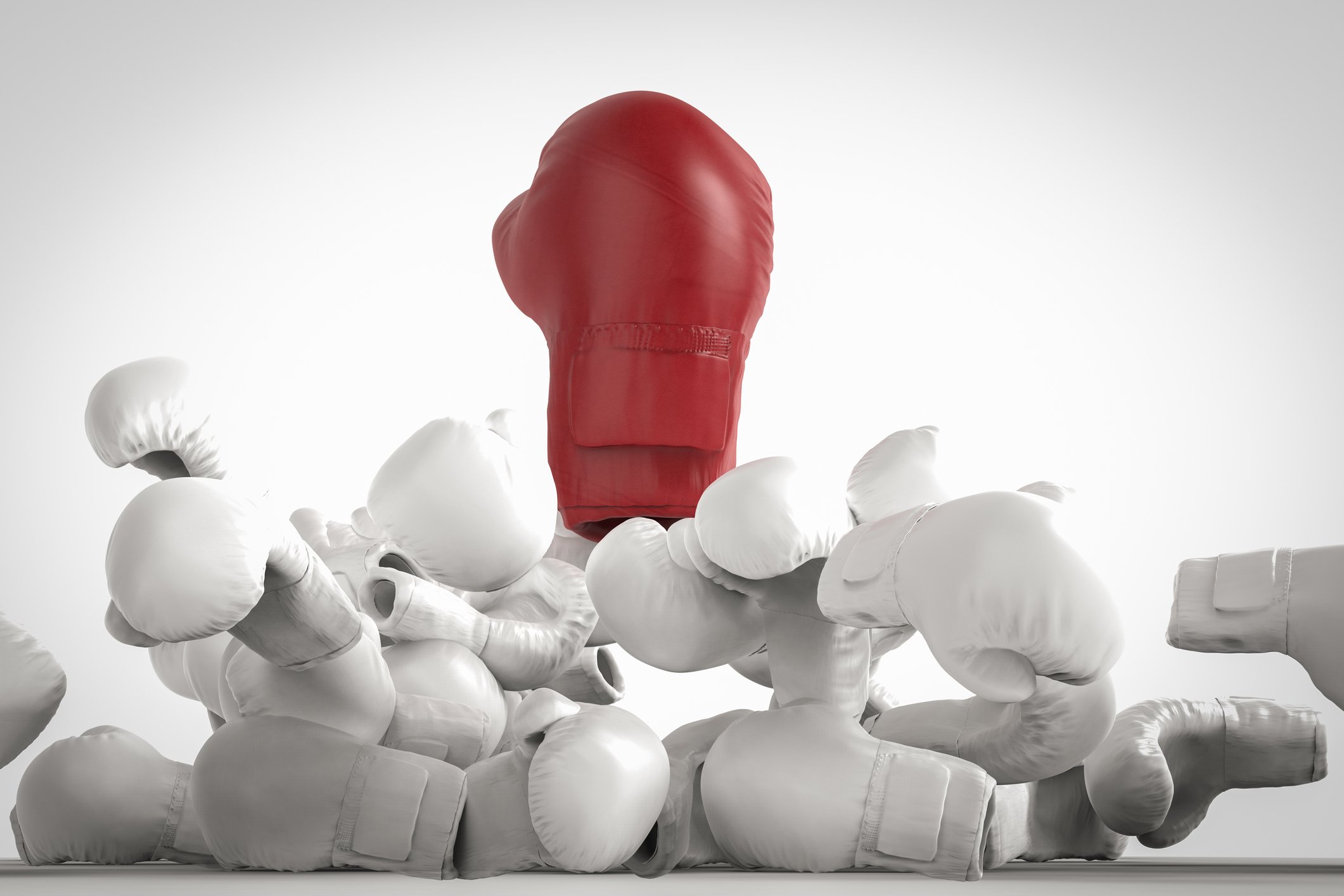 A red boxing glove bursts out through a pile of smaller white boxing gloves.
