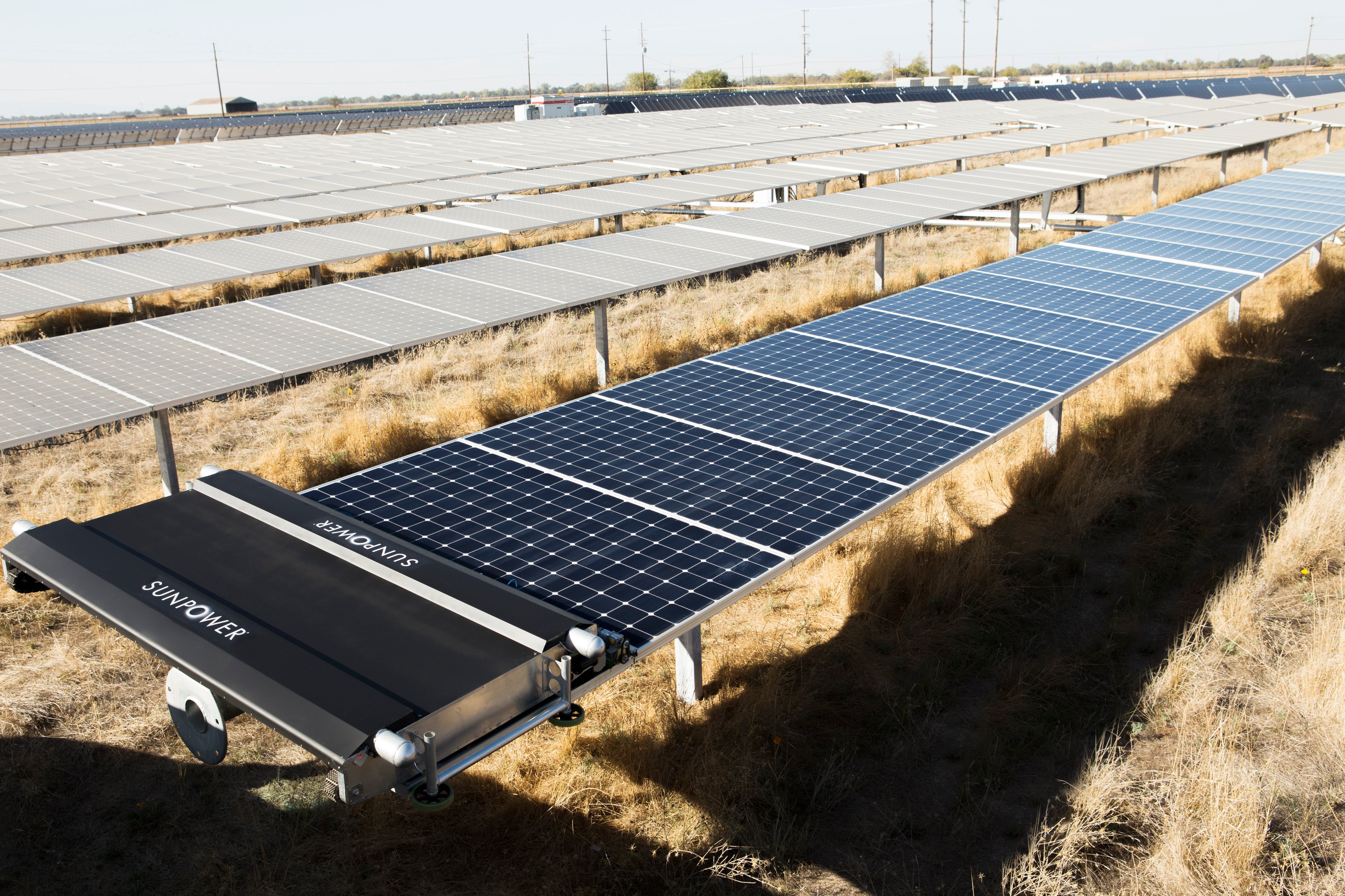 Utility scale solar farm with a robotic cleaner on the first row of panels. 