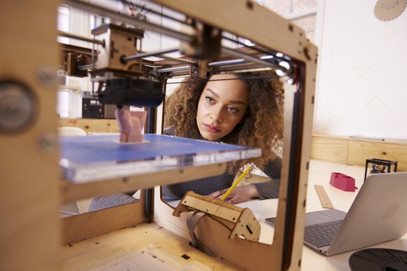 Woman looking at 3D printer.