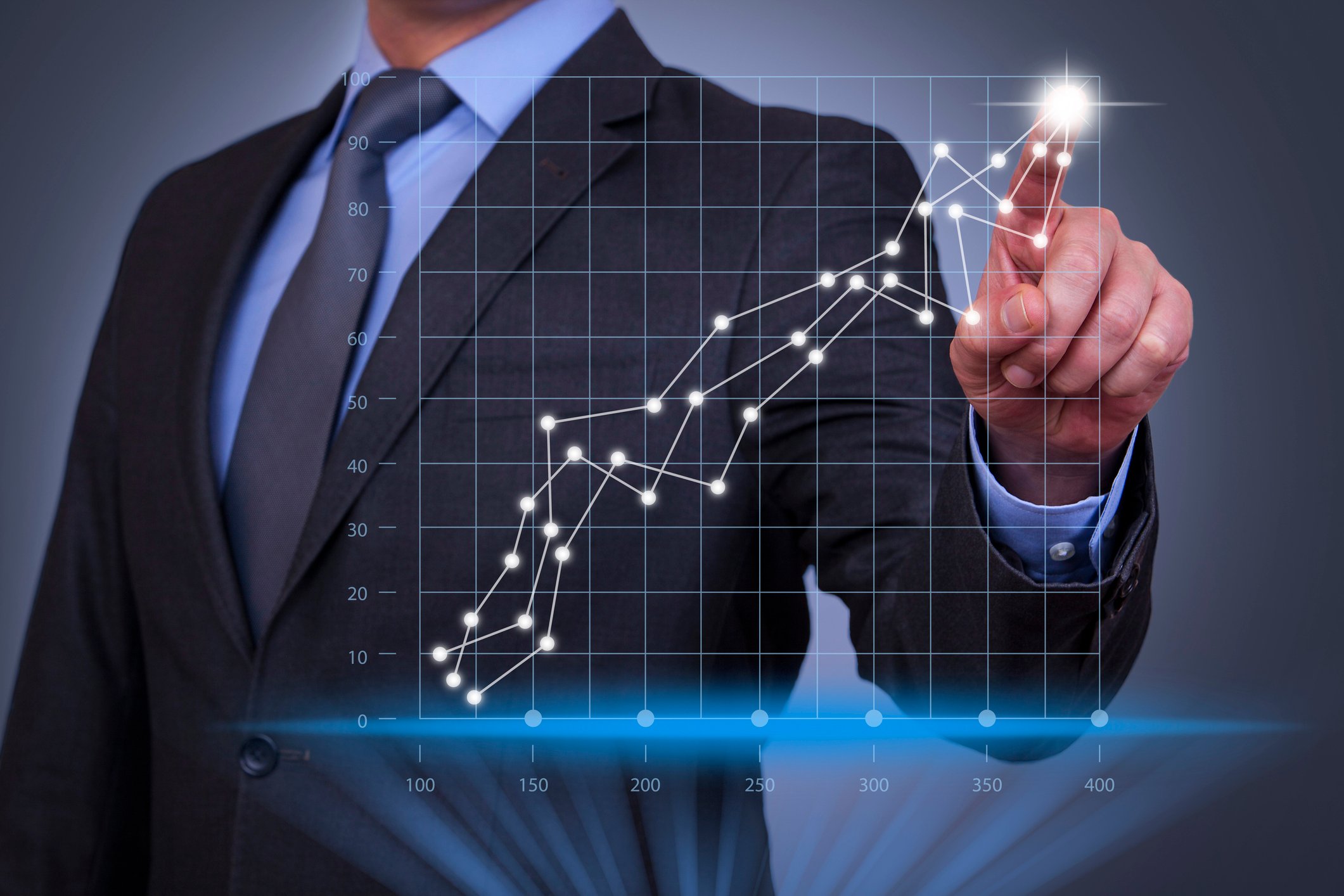 Man in a business suit pointing to an upward trending graph.