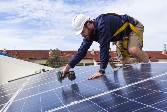 Worker installing solar panels on a roof. 