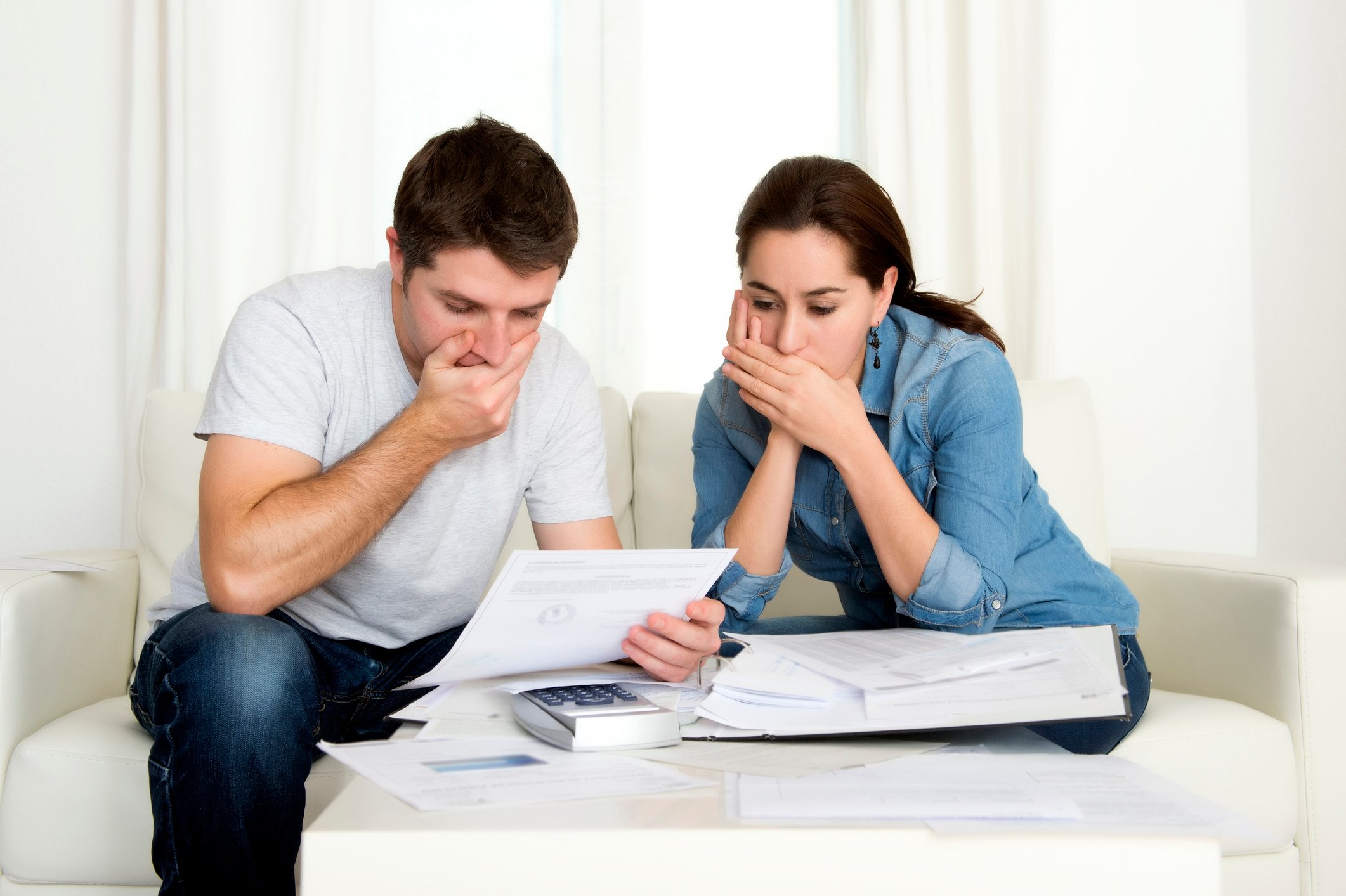 Couple covering their mouths while looking at papers