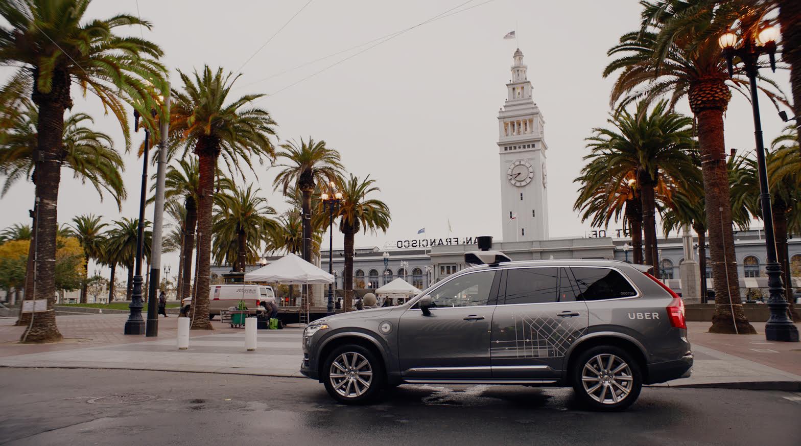 A gray Volvo SUV with visible self-driving sensor hardware and Uber logos parked on a street in San Francisco.